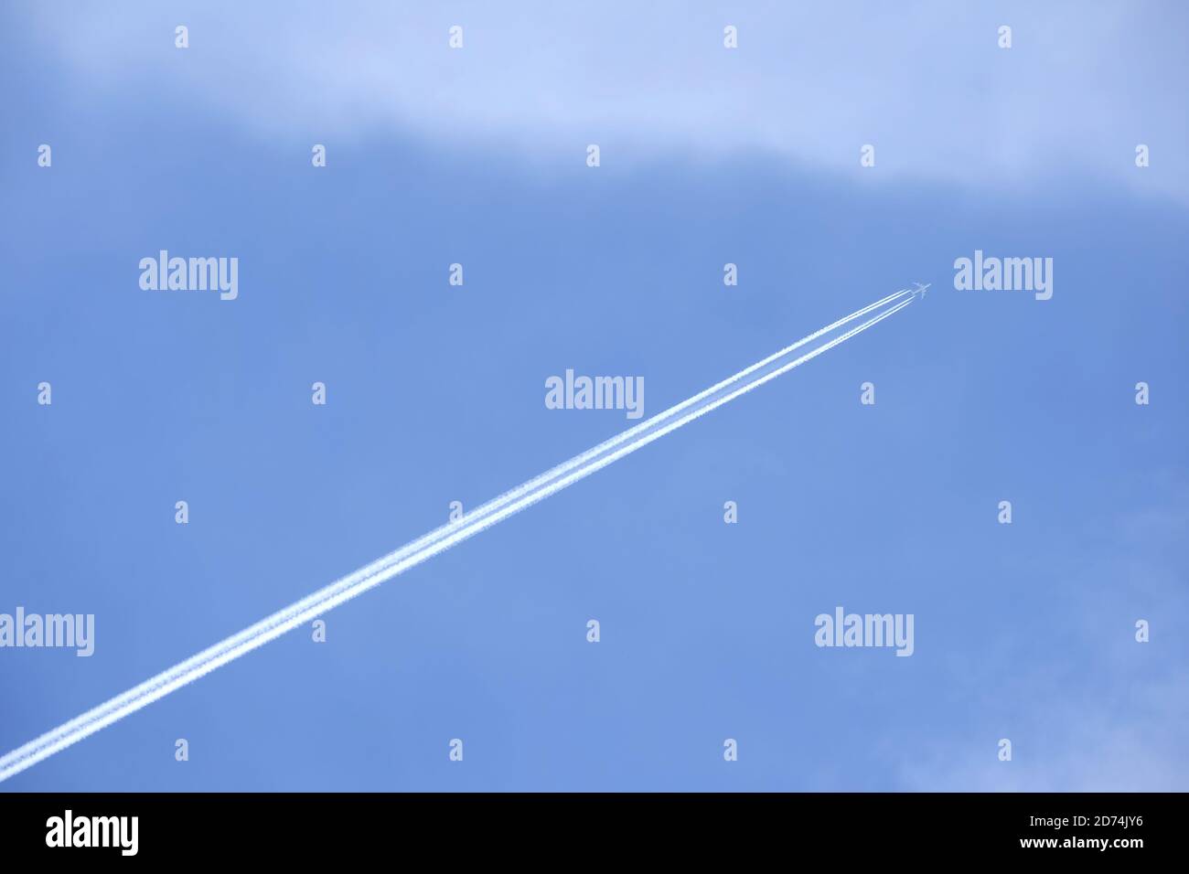 Aereo supersonico per grandi passeggeri con quattro motori a getto che volano in alto in cielo azzurro limpido e senza nuvole, lasciando una lunga traccia bianca Foto Stock