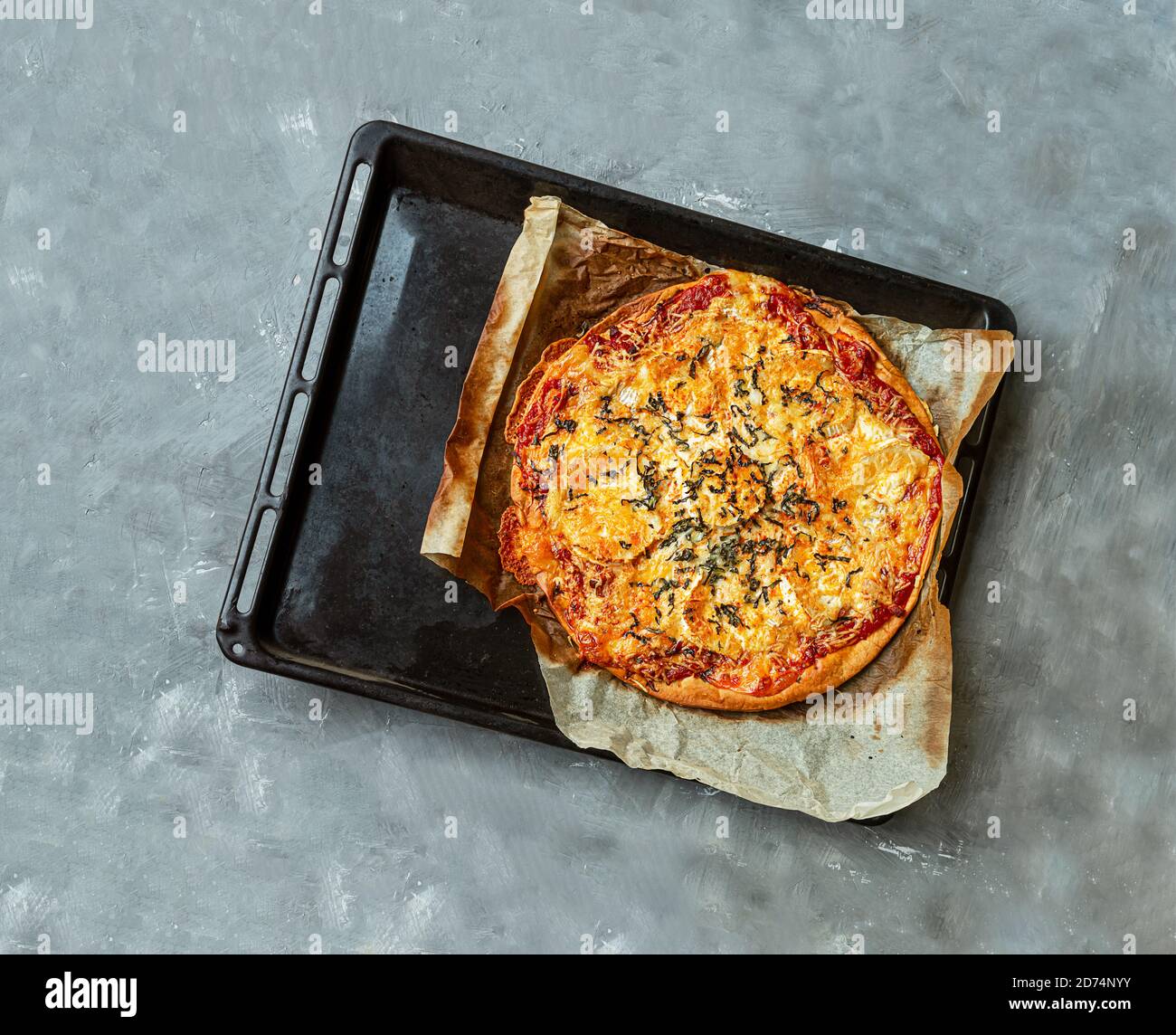 Pizza fatta in casa con pancetta, formaggio di capra e basilico su una teglia su un tavolo grigio. Vista dall'alto Foto Stock