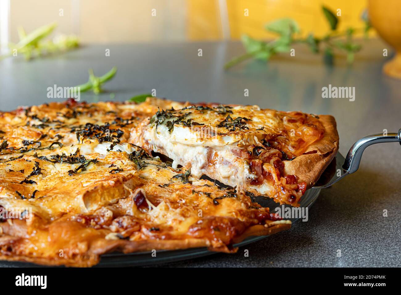 Fetta di pizza fatta in casa con formaggio di capra fondente e basilico su un tavolo grigio. Foto Stock