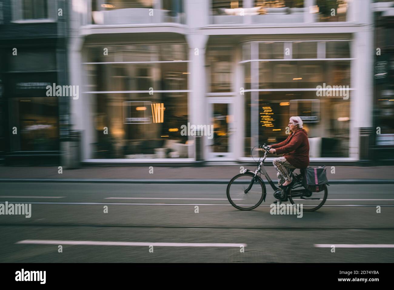 Donna in bicicletta per le stradine strette di Amsterdam durante i primi spostamenti mattutini. Paesi Bassi Foto Stock