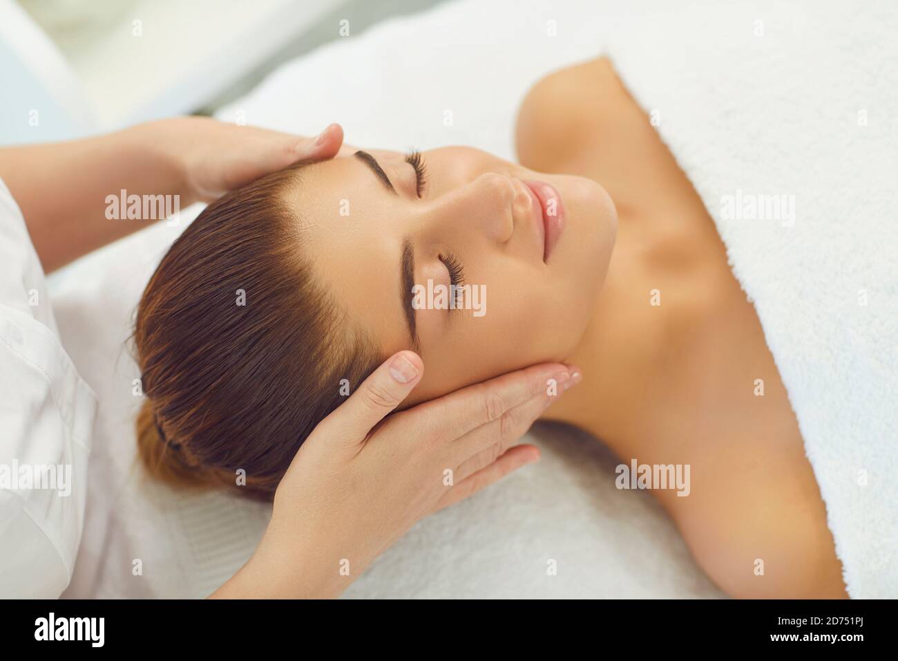 Faccia sorridente delle donne che ottiene il massaggio manuale professionale di distensione dalle mani di massaggiatore Foto Stock