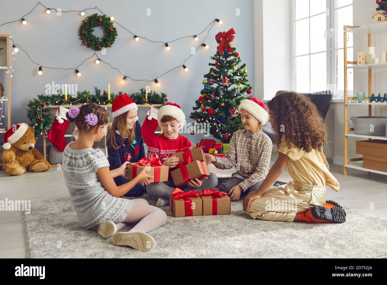 Gruppo di bambini amici scambiano regali il giorno di Natale seduto in soggiorno. Foto Stock