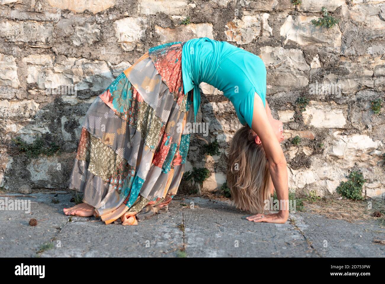 Donna adulta fa esercizio sportivo. Insegnante di yoga che fa un asana sulle mura della città vecchia. Foto Stock