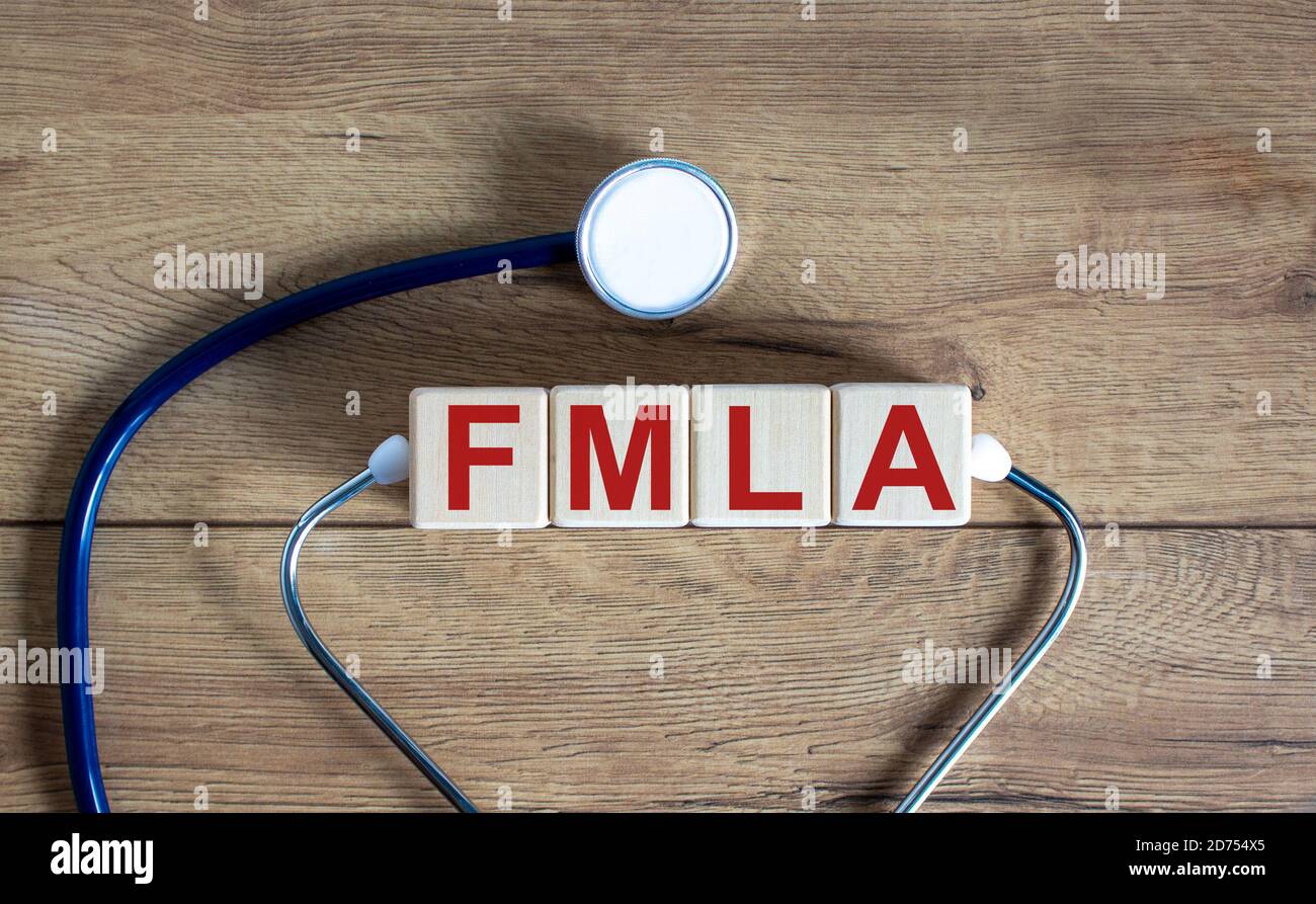 Concetto parola 'FMLA, famiglia congedo medico atto' su cubi su uno sfondo di legno bello. Stetoscopio. Spazio di copia, concetto medico. Foto Stock