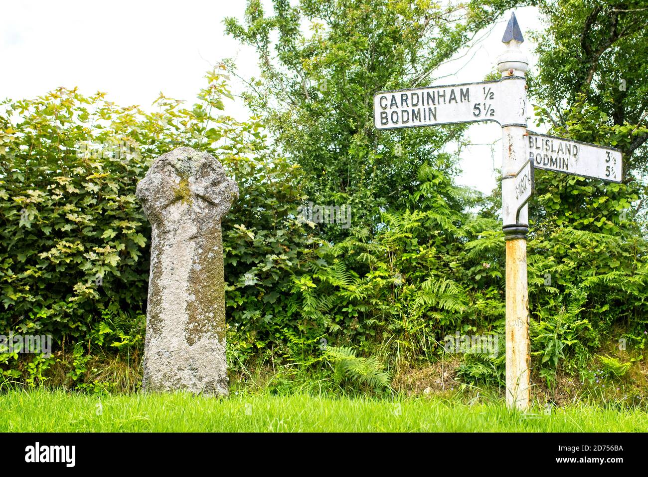 Antica croce di pietra e un vecchio cartello stradale 'fingerpost' ad un incrocio stradale vicino a Bodmin, Cornovaglia, Inghilterra, Regno Unito. Foto Stock
