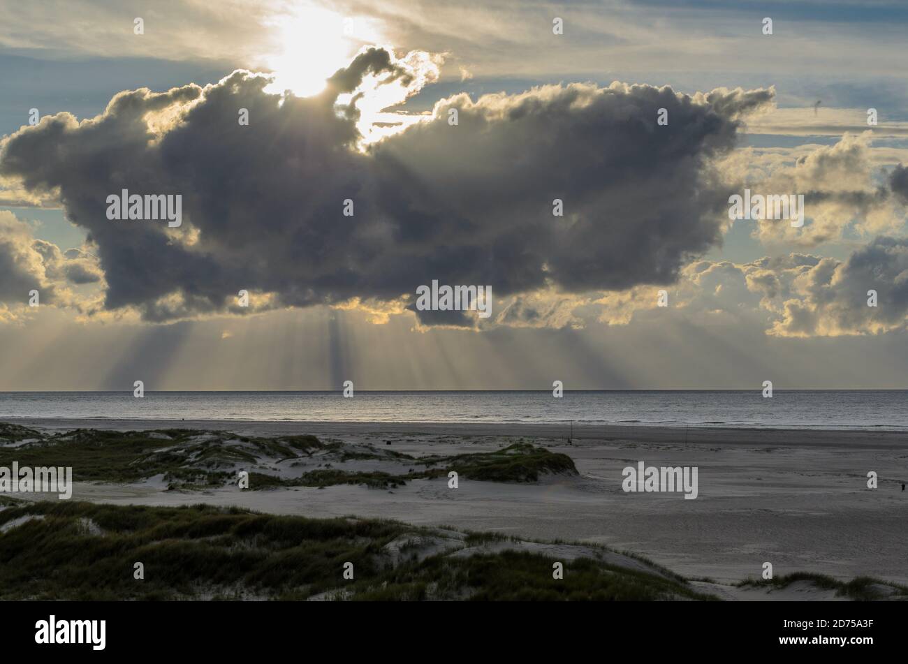 Amrum Island, Germania: Raggi del sole che emergono attraverso le nubi buie della tempesta alla spiaggia di Amrum. Il tramonto è oscurato da una fitta nuvola anteriore che annuncia male Foto Stock