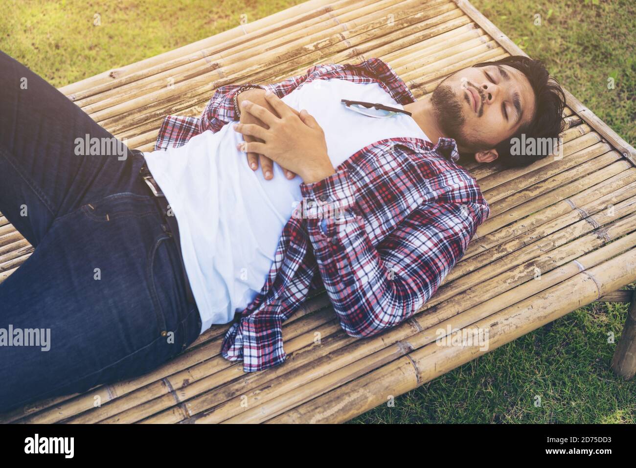 Il giovane uomo dorme su letto di bambù, seduta, tavolo o lettino fatto di materiale naturale. Natura, relax e concetto Dormi bene. Il daydreamer sogna Foto Stock