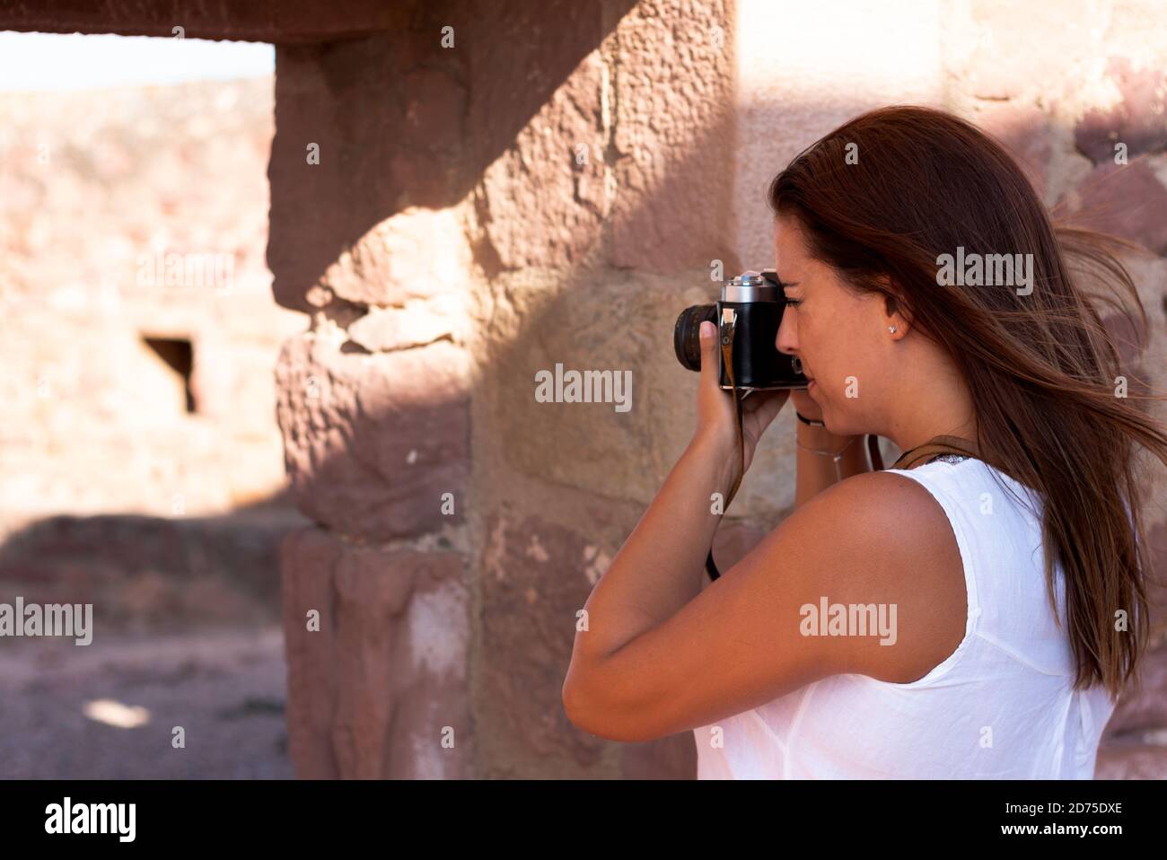 Una giovane donna in abito bianco che fotografa con una vecchia macchina fotografica per strada. Concetto di fotografia Foto Stock