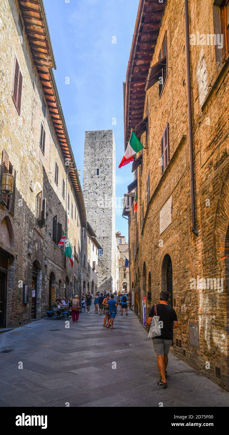 Centro storico di San Gimignano, sito dell'UNESCO, con i turisti a piedi in un vicolo stretto e la medievale Torre dei Cugnanesi, Siena, Toscana, Italia Foto Stock