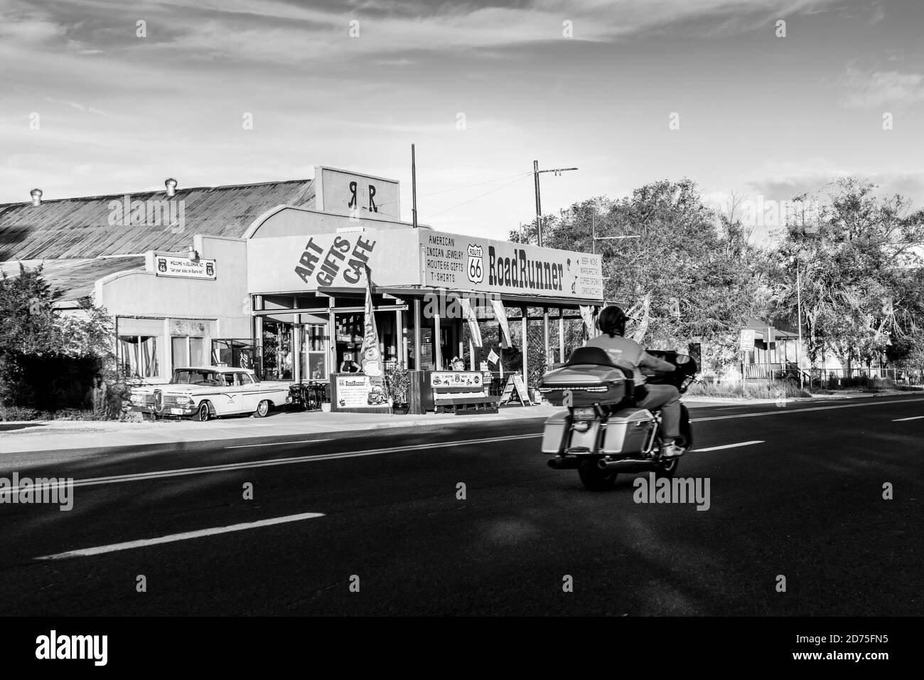 Seligman USA - Settembre 29 2015; Biker si è offuscato come pass Road Runner cafe e negozio di souvenir in un viaggio su strada, mentre l'ombra mattutina copre ancora la strada Foto Stock