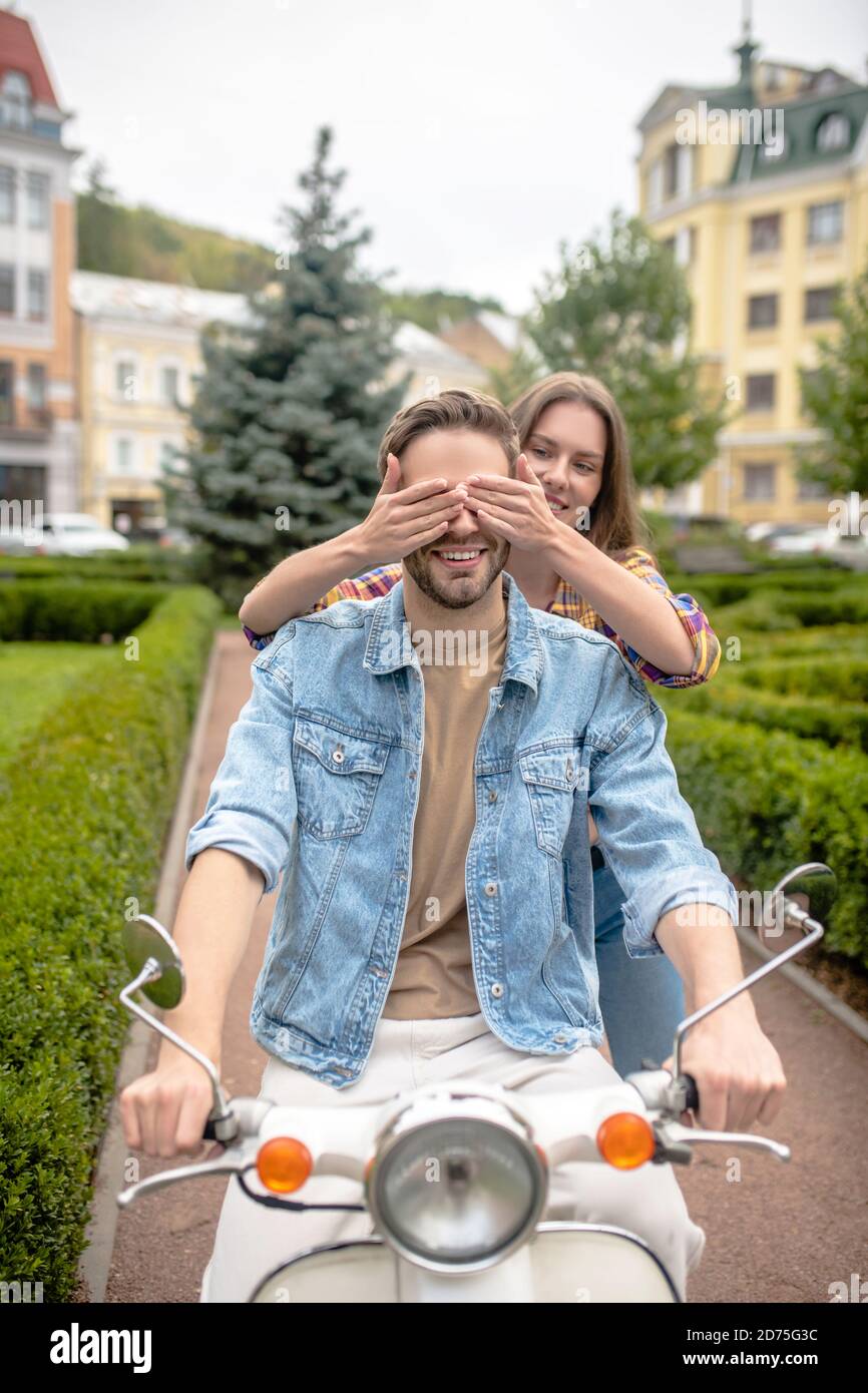Donna che si diverte con l'uomo che guida uno scooter Foto Stock