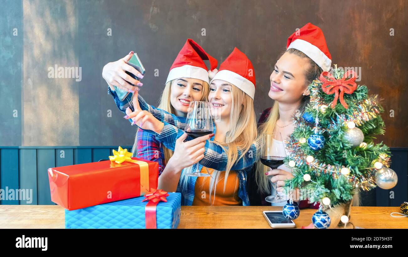 Felici giovani donne che si divertono a prendere un selfie durante Natale festa al ristorante Foto Stock