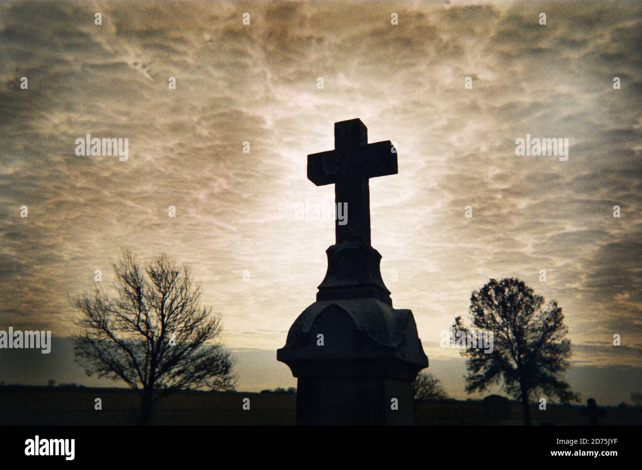 Marcatore di tomba in un cimitero vicino ad una Chiesa cattolica. Foto Stock