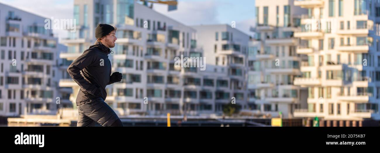 City lifestyle inverno run atleta corridore uomo jogging all'esterno su moderno edificio appartamento sfondo banner panoramico. Gestione di persone viventi attive Foto Stock