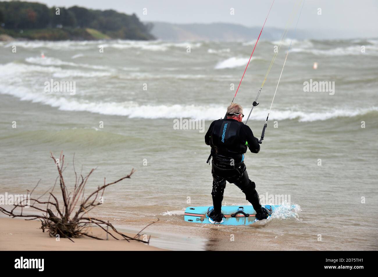 South Haven, Michigan, Stati Uniti. Un parasailer maschile lungo la spiaggia di South Haven lavorando per fare il suo paracadute prendere il vento e portarlo nel lago. Foto Stock