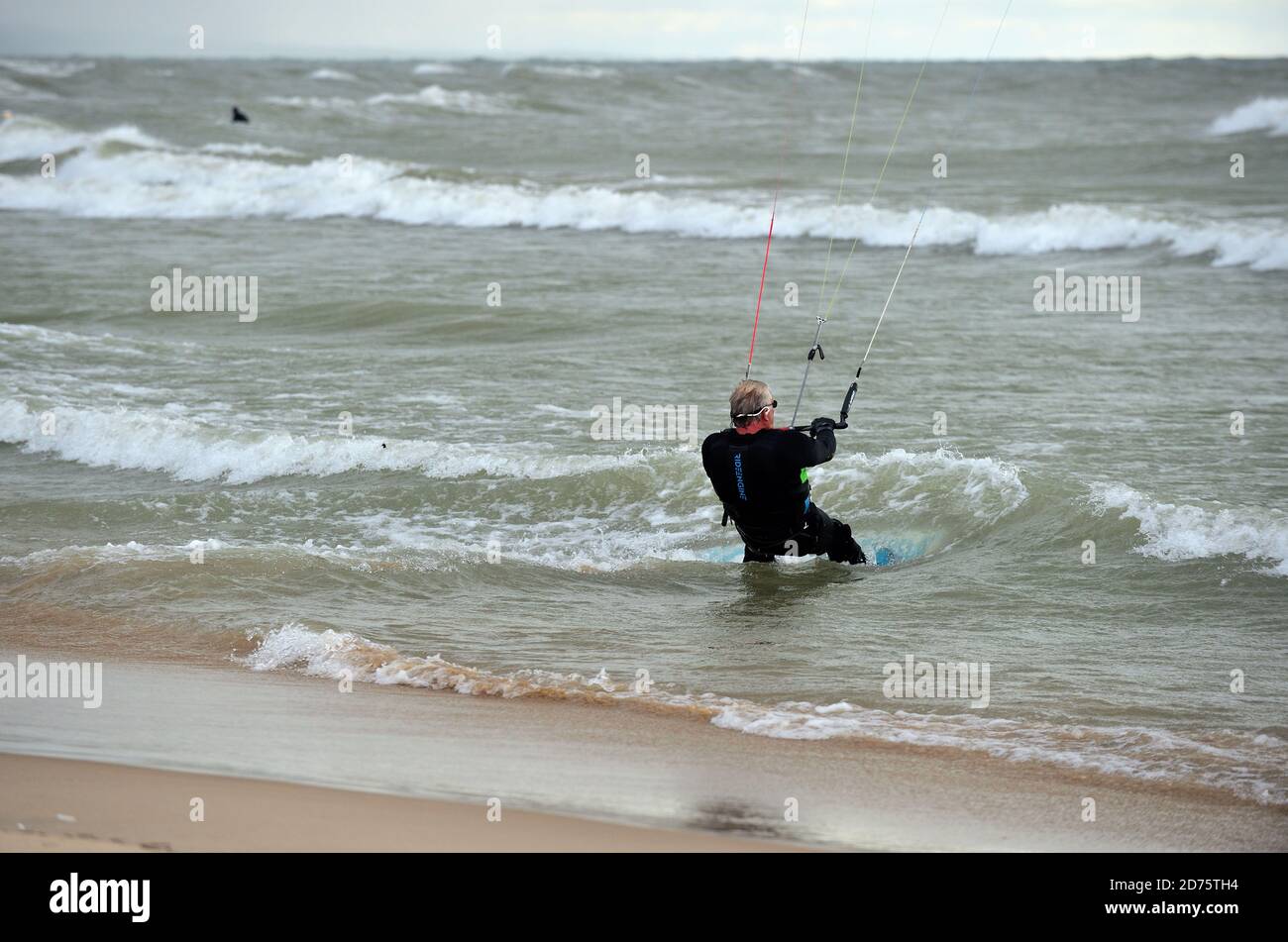 South Haven, Michigan, Stati Uniti. Un parasailer maschile lungo la spiaggia di South Haven lavorando per fare il suo paracadute prendere il vento e portarlo nel lago. Foto Stock