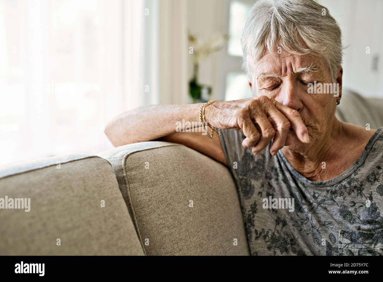 Ritratto di piangere donna anziano su divano che soffre di depressione Foto Stock