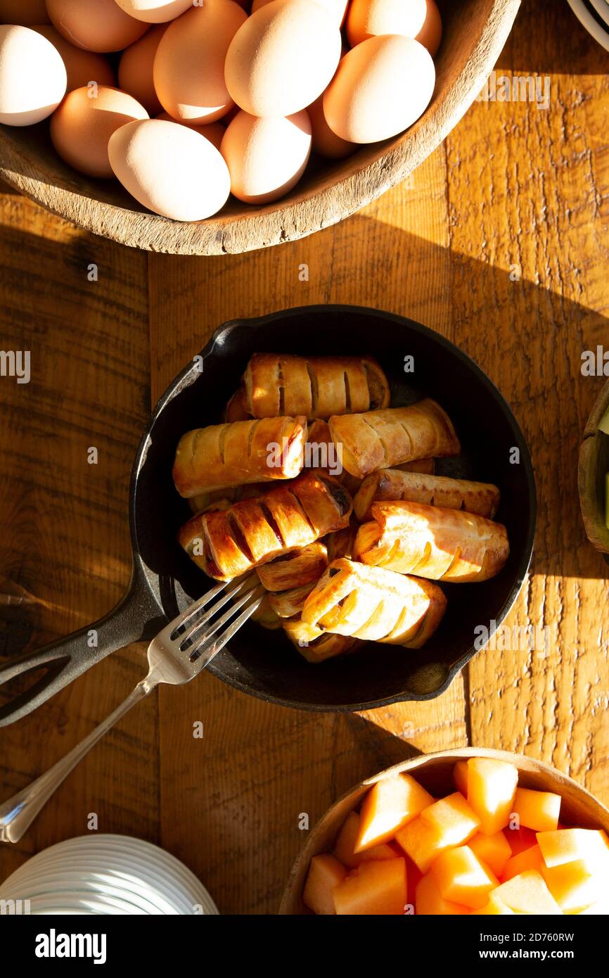 Vista ad alta angolazione dei pasticcini di mele nella padella in ghisa E ciotole di uova e Cantalupe Foto Stock