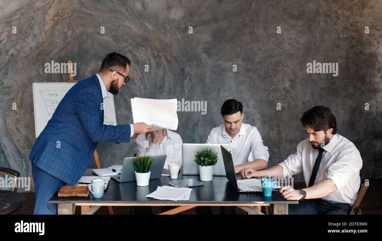 Arrabbiato boss rimprovero dipendente per il cattivo lavoro risultato seduto al tavolo della conferenza, uomo ceo scolding incompetente manager incolpando per errore in Foto Stock