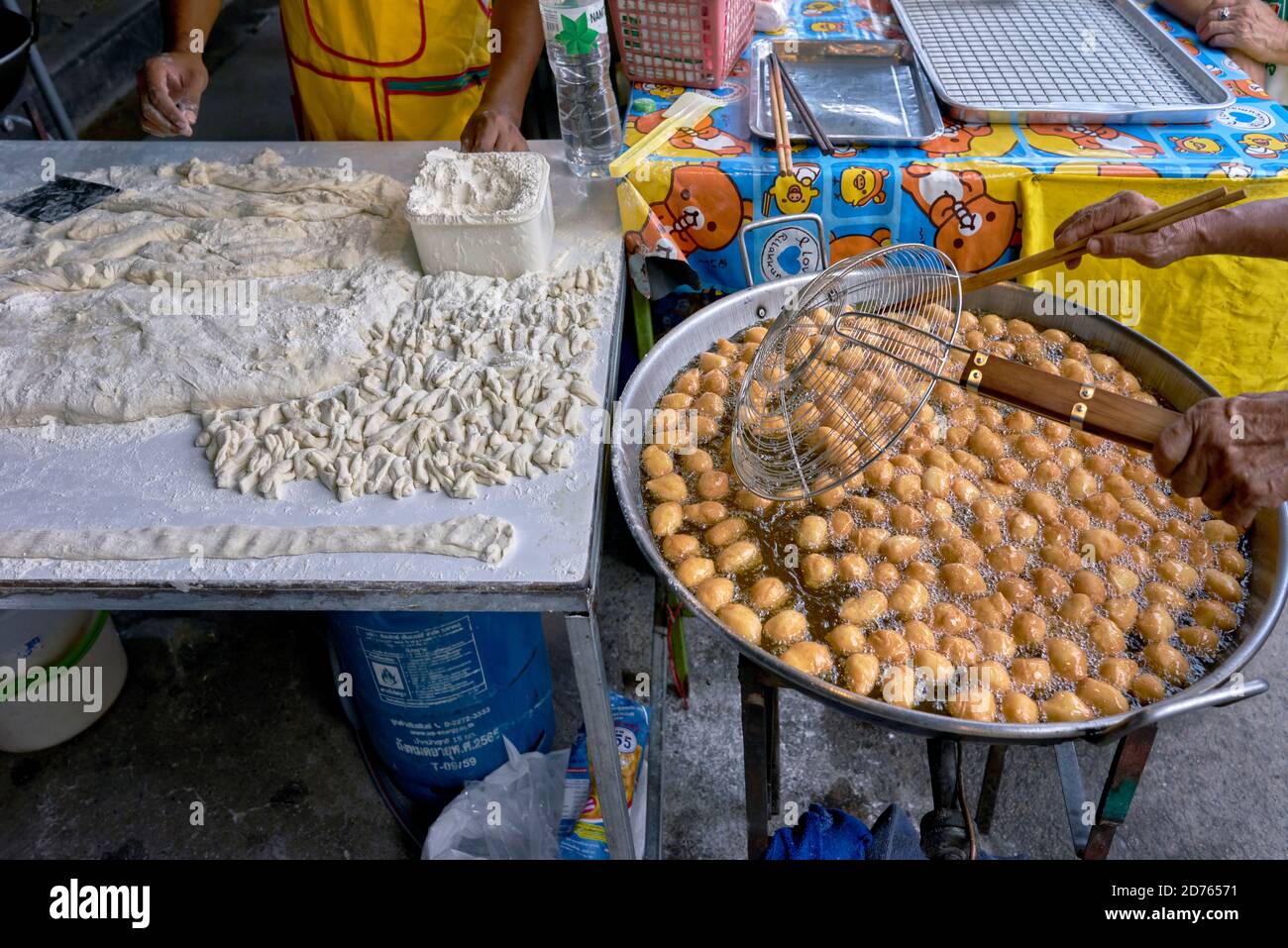 Panettiere preparazione di palle di pane zuccherate fritte popolari come spuntino Un complemento per il caffe' alimentare in un mercato alimentare di strada in Thailandia Foto Stock