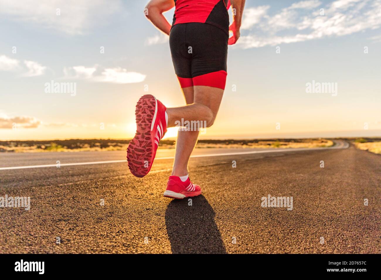 Scarpe da running su corridore triatleta maschile - closeup di piedi che corrono su strada. L'uomo che fa jogging all'esterno esercitandosi addestrando per l'ironman di triathlon all'esterno a. Foto Stock