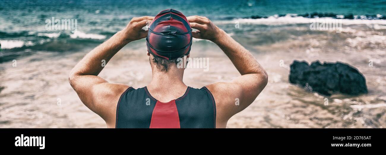 Nuotatore in preparazione per la gara di nuoto oceano aperto durante il triathlon. Atleta da dietro indossare gli occhiali di protezione. Banner panoramico Foto Stock