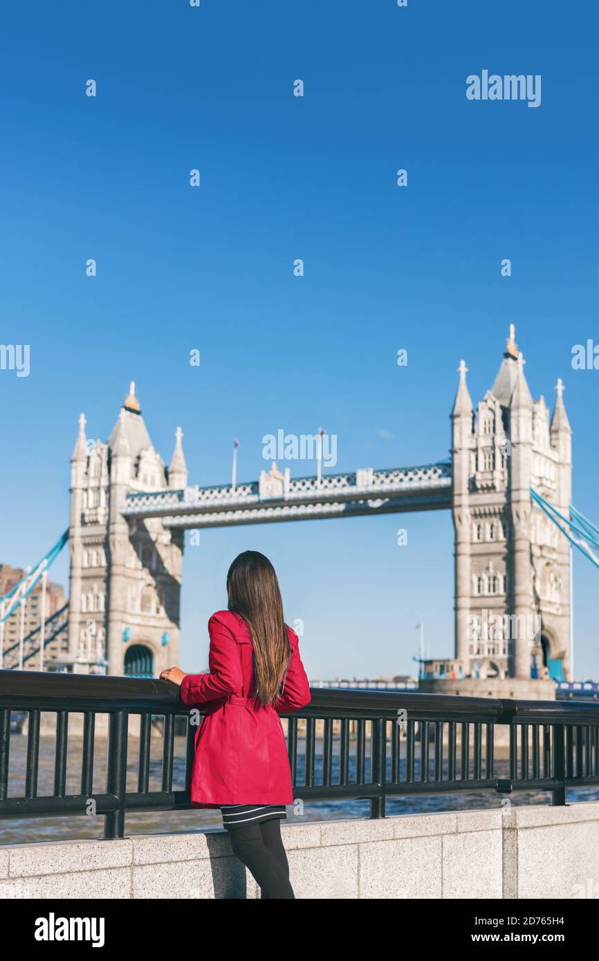 La gente di Londra la donna turistica della città che guarda la vista del Ponte della Torre in un cappotto di trincea rosso. Ponte. Elegante donna moda ragazza che cammina Foto Stock
