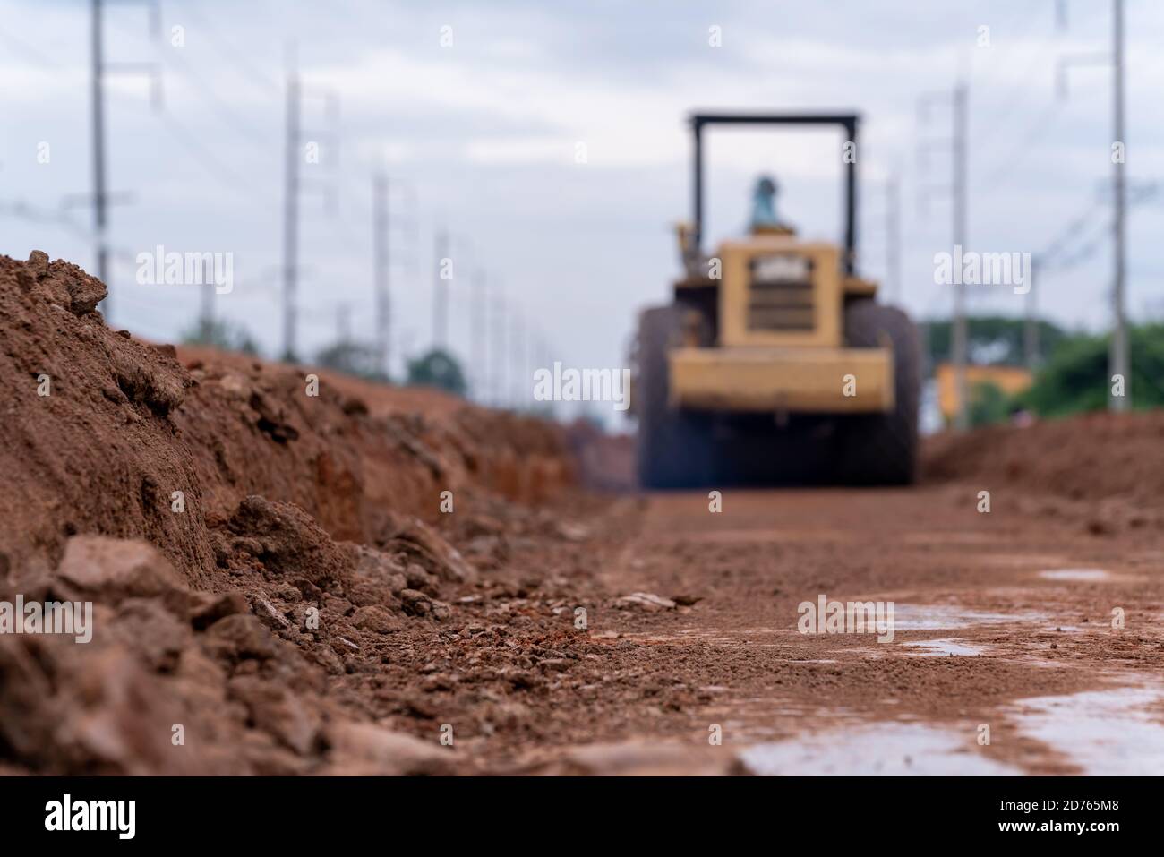 Compattatore vibrante per terreno giallo offuscato che lavora sulla costruzione di strade, compattatore vibrante per terreno giallo nel cantiere stradale Foto Stock