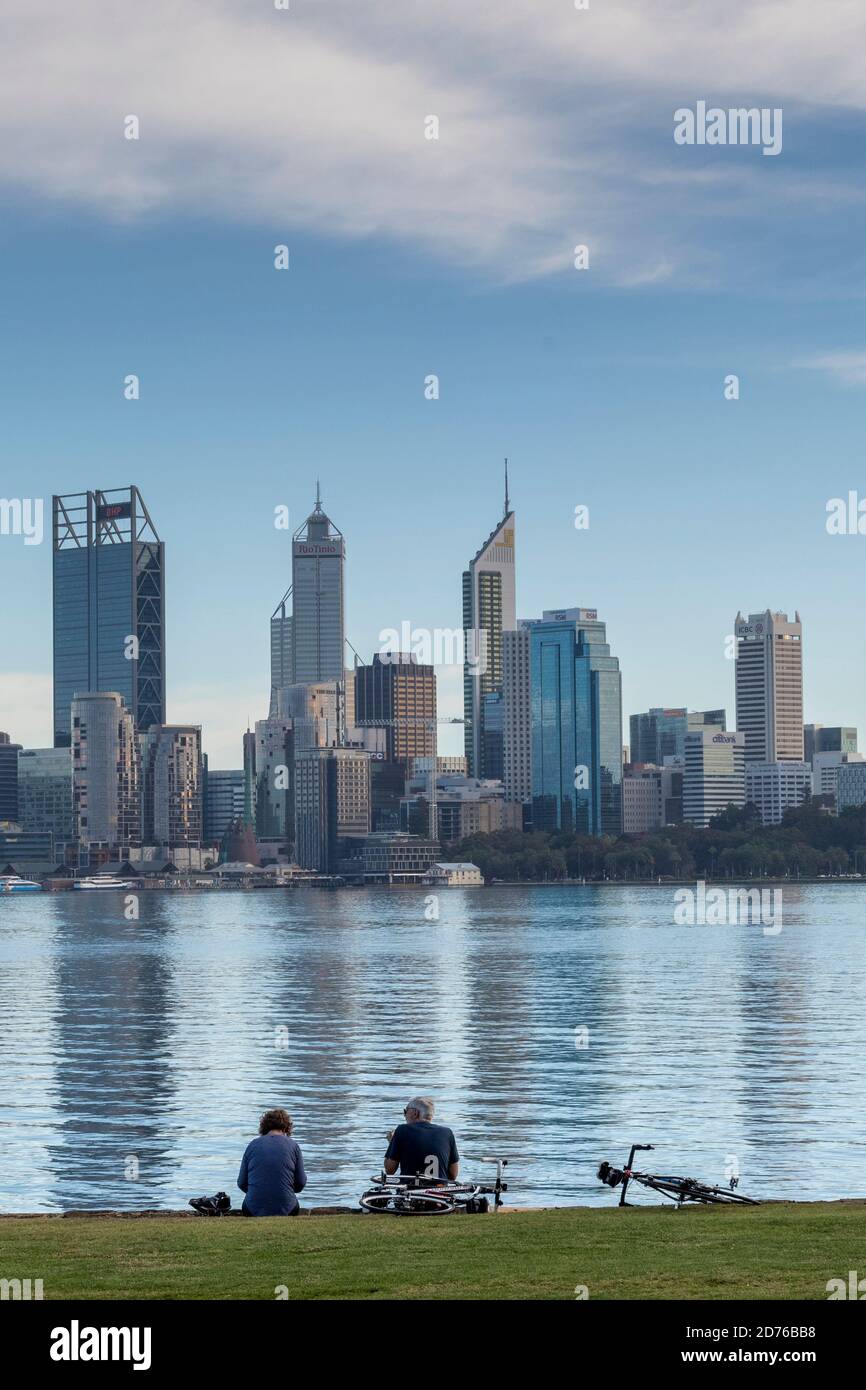 Le coppie siedono sulle rive del fiume Swan di fronte al CBD di Perth. Foto Stock