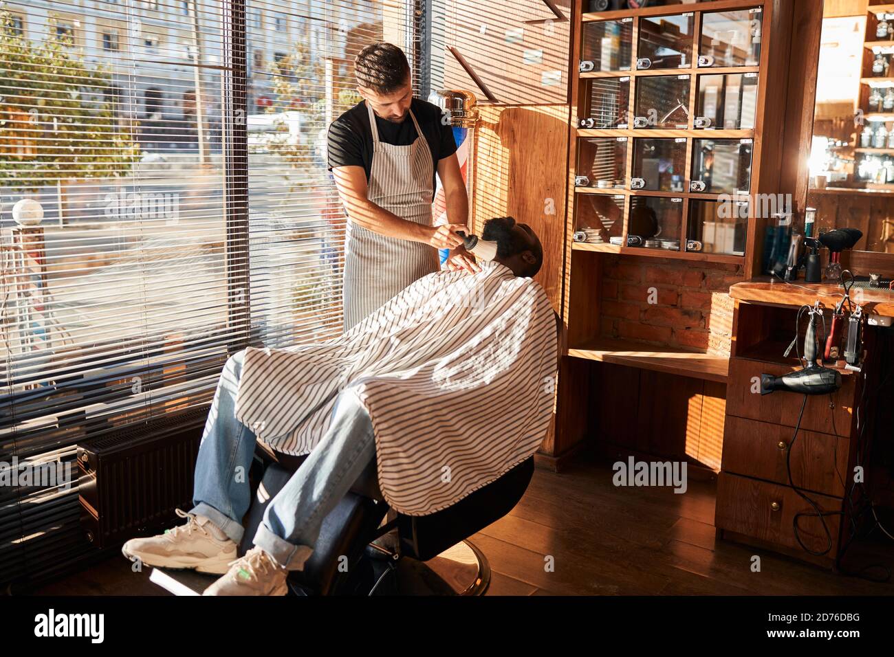 Barbiere rimozione dei peli superflui dalla barba del cliente dopo la rifinitura Foto Stock