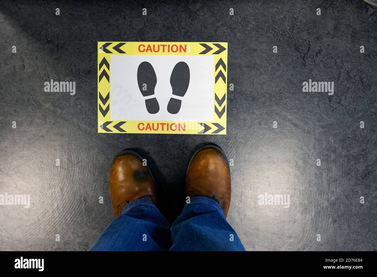 Coppia di piedi davanti al cartello di avvertenza attenzione Foto Stock