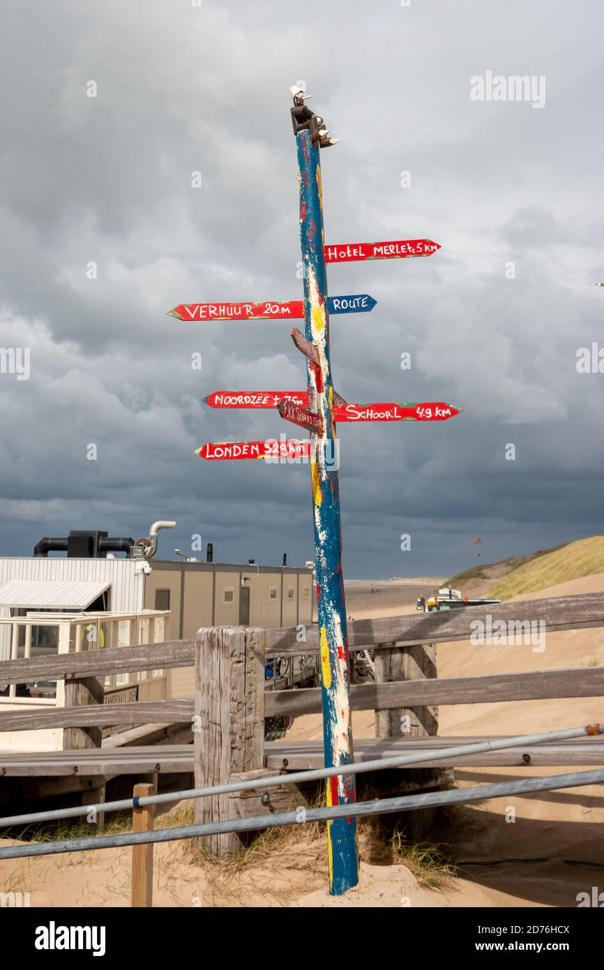 Cartelli stradali dai colori vivaci su un palo di legno sulla spiaggia del Mare del Nord nella provincia di Noord Holland, Paesi Bassi Foto Stock