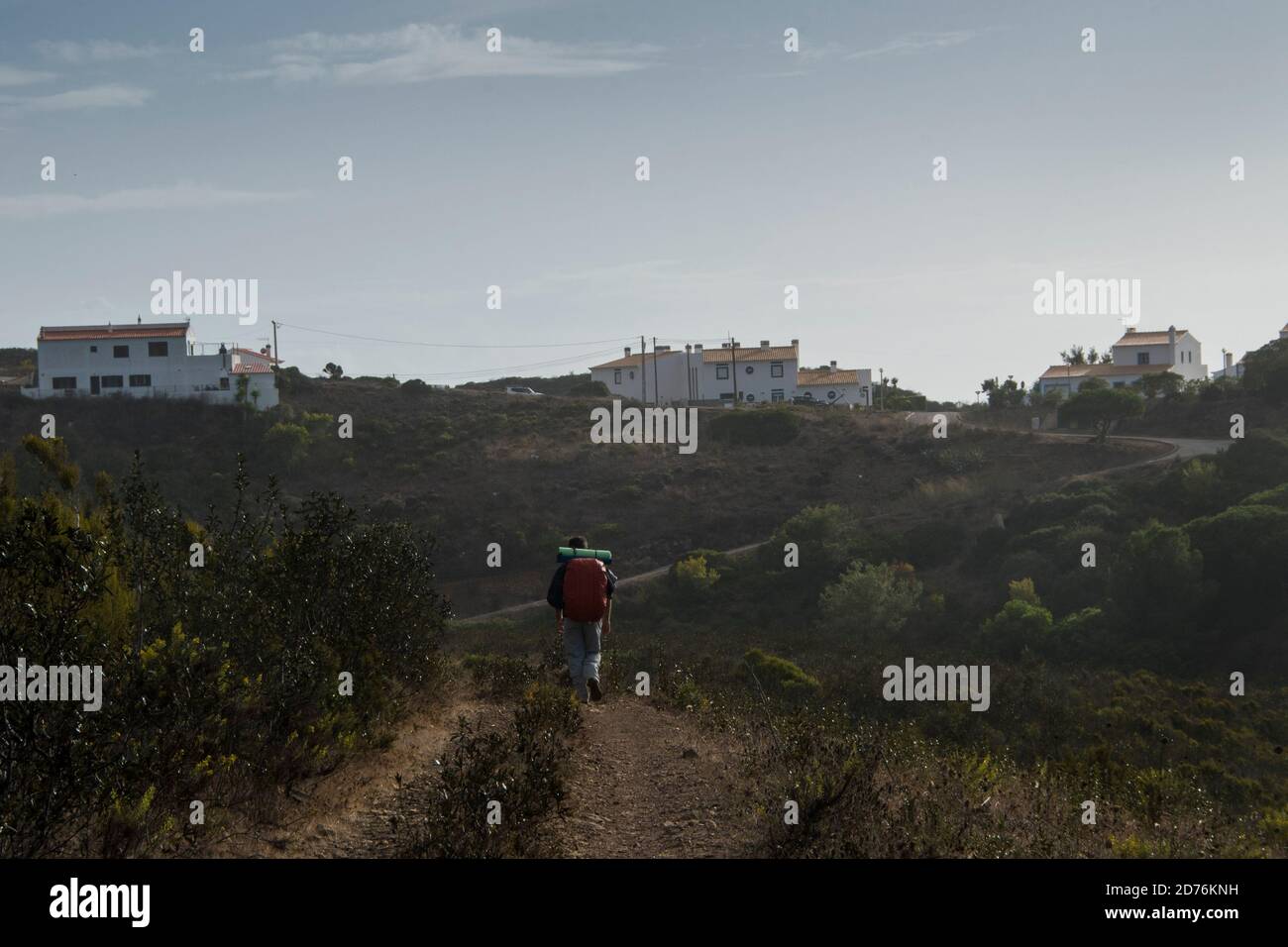 Escursionista passeggiate lungo il sentiero con uno zaino che si avvicina a. città vicina Foto Stock