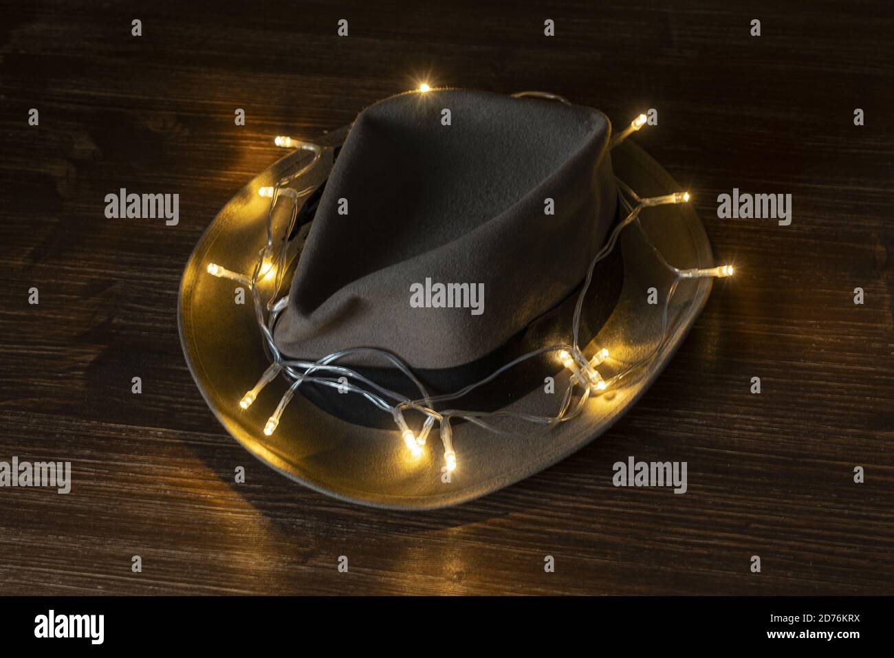 un vecchio cappello con una fila di piccole luci avvolte con sfondo in legno Foto Stock