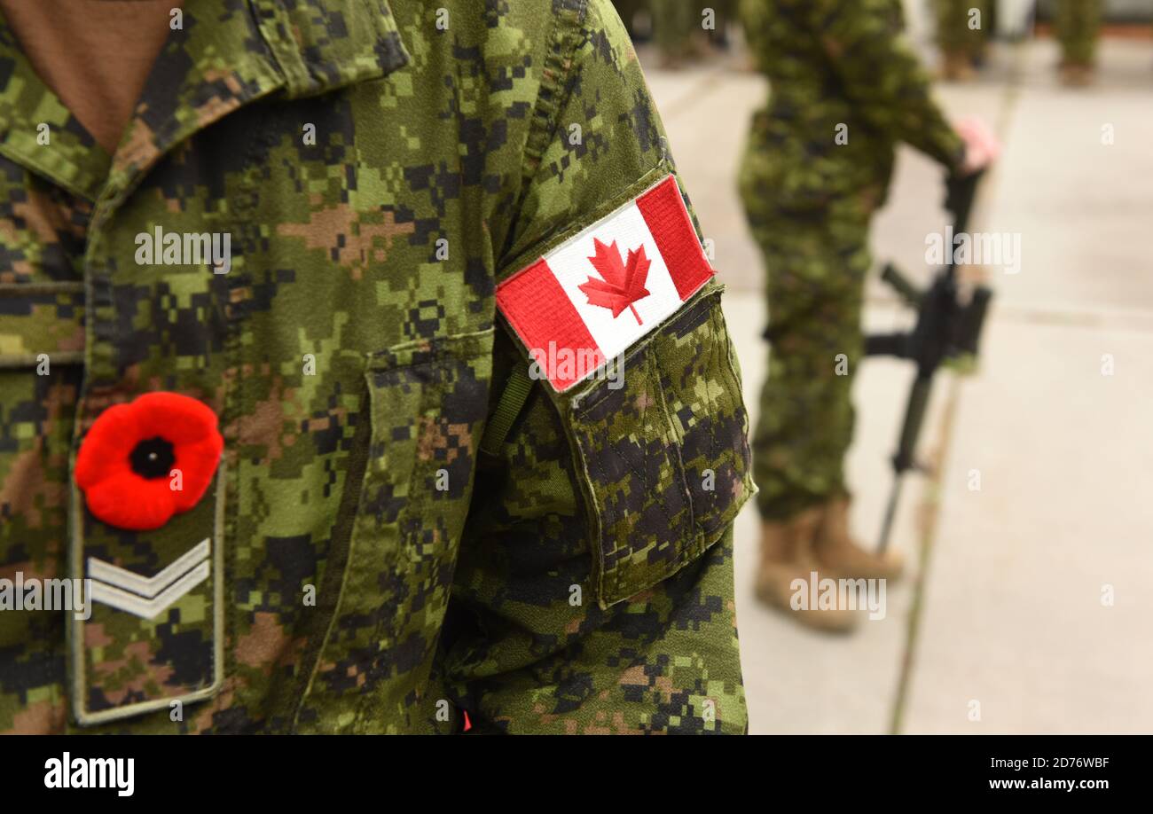 Bandiera del Canada in uniforme militare e soldato con arma sullo sfondo. Soldati canadesi. Esercito canadese. Giorno del Ricordo. Canada giorno. Foto Stock