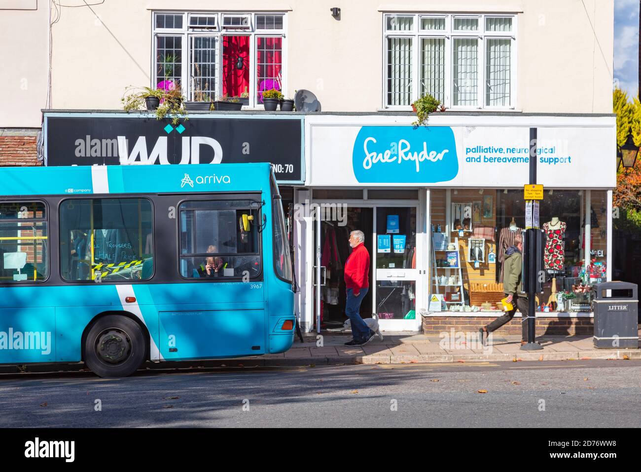 Un autobus blu parcheggiato all'esterno di un negozio di beneficenza sue Ryder con un cartello blu corrispondente, su Tenterden High Street, Kent, UK Foto Stock