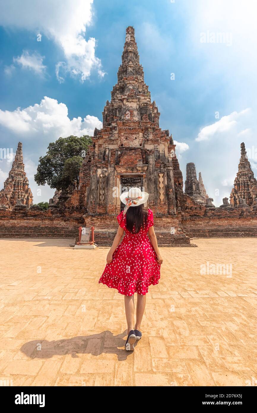 Donna turistica asiatica in abito rosso e cappello da sole dalla vista posteriore, a piedi attraverso il bellissimo castello di storia e tempio storico a Ayutthaya, Thailandia Foto Stock