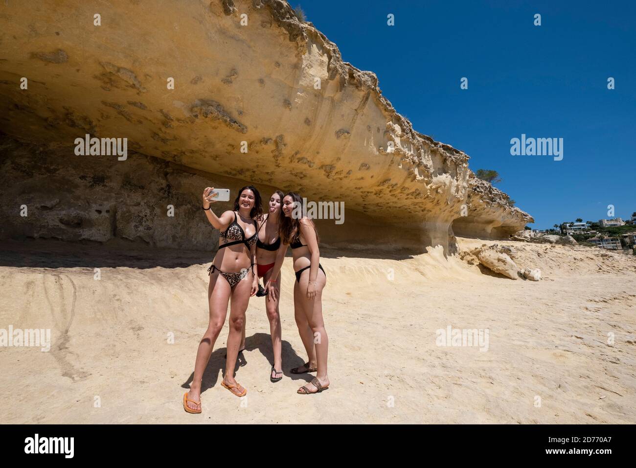 Tre ragazze adolescenti che prendono un selfie dalle rocce di arenaria, Cala Portals Vells, Calvia, Mallorca, Isole Baleari, Spagna Foto Stock