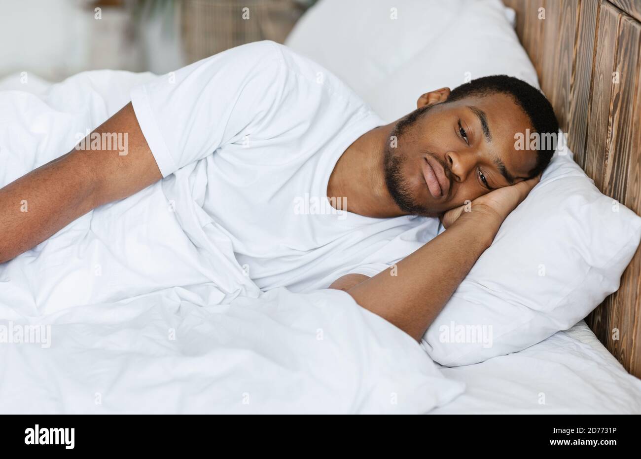 Depresso Guy nero mentire avendo Insomnia in Camera da letto a casa Foto Stock