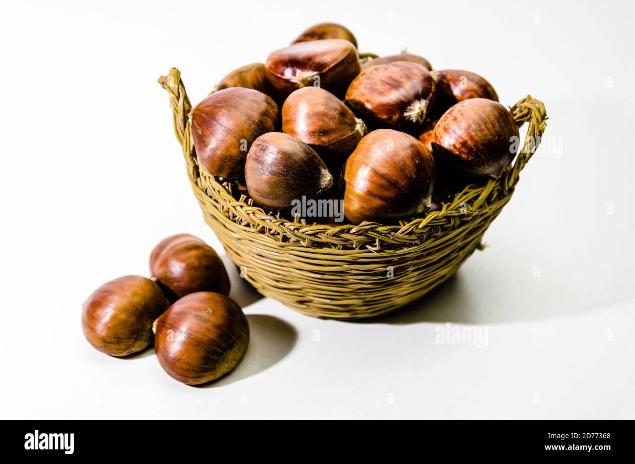 Le castagne in cesto in vimini su sfondo bianco Foto Stock