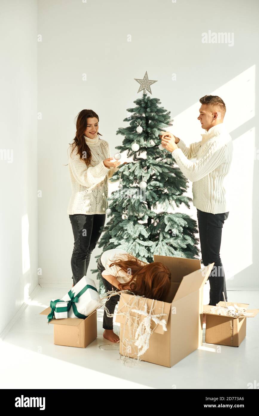 Felice famiglia che decorano l'albero di Natale a casa Foto Stock