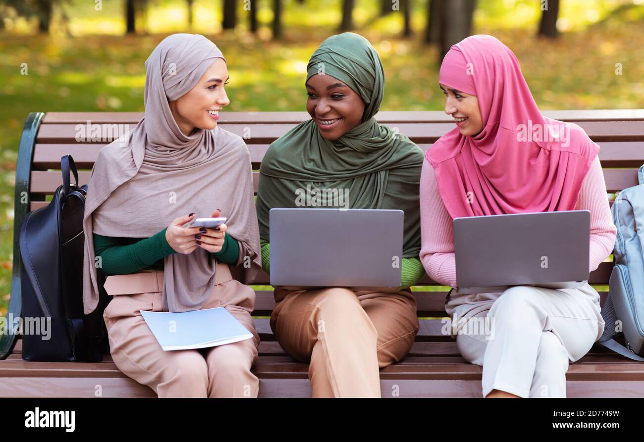 Musulmana studenti di sesso femminile che usano notebook e smartphone imparare insieme fuori Foto Stock
