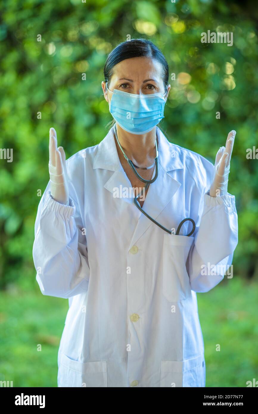 Sicuro medico femminile nel giardino dell'ospedale che indossa la maschera di salute e guanti per le mani. Foto Stock