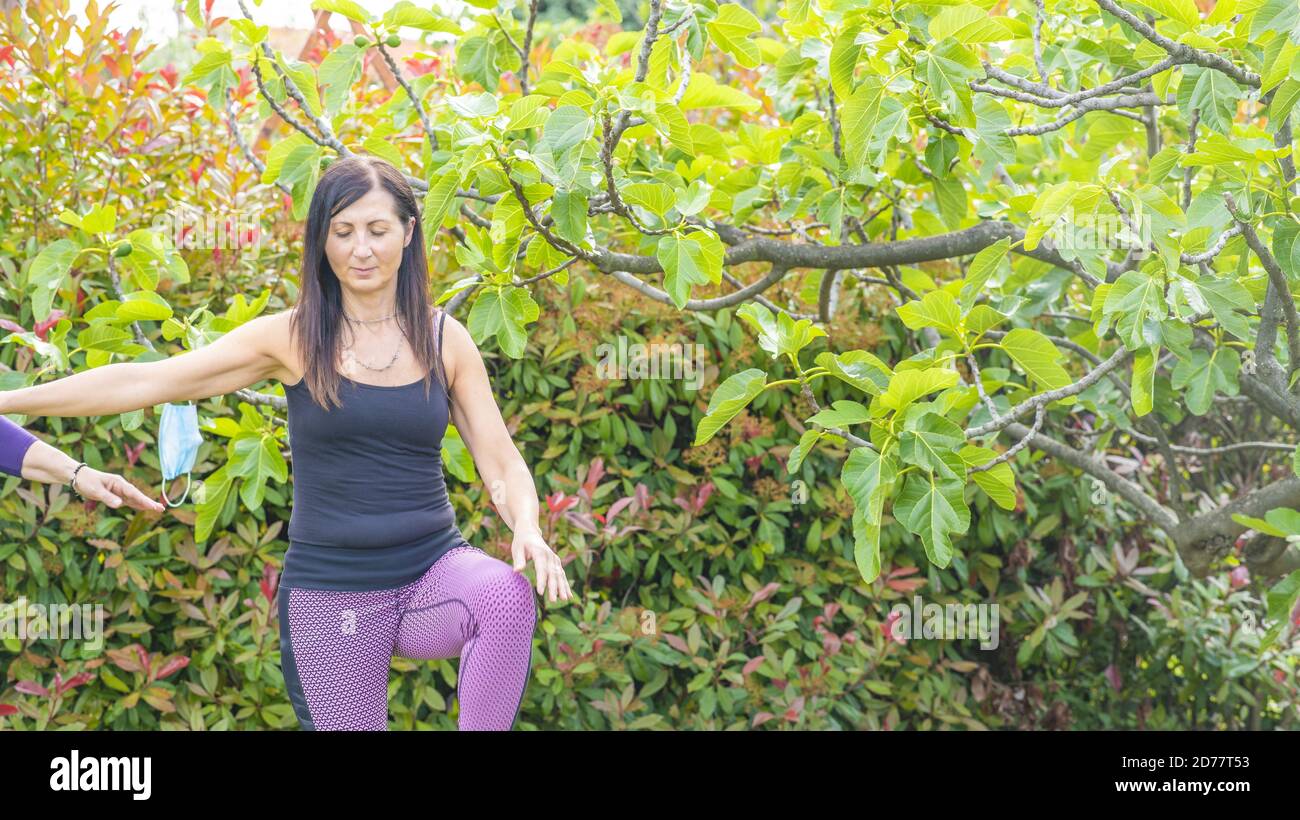 Donna che ha il fitness domestico all'aperto, maschera di salute sullo sfondo. Foto Stock