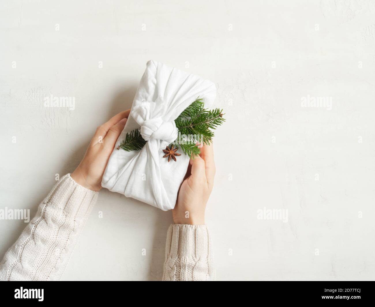 Le mani della donna tengono Natale riutilizzabile dono sostenibile. Confezione regalo riutilizzabile per Natale. Concetto di zero sprechi. Spazio di copia. Vi Foto Stock