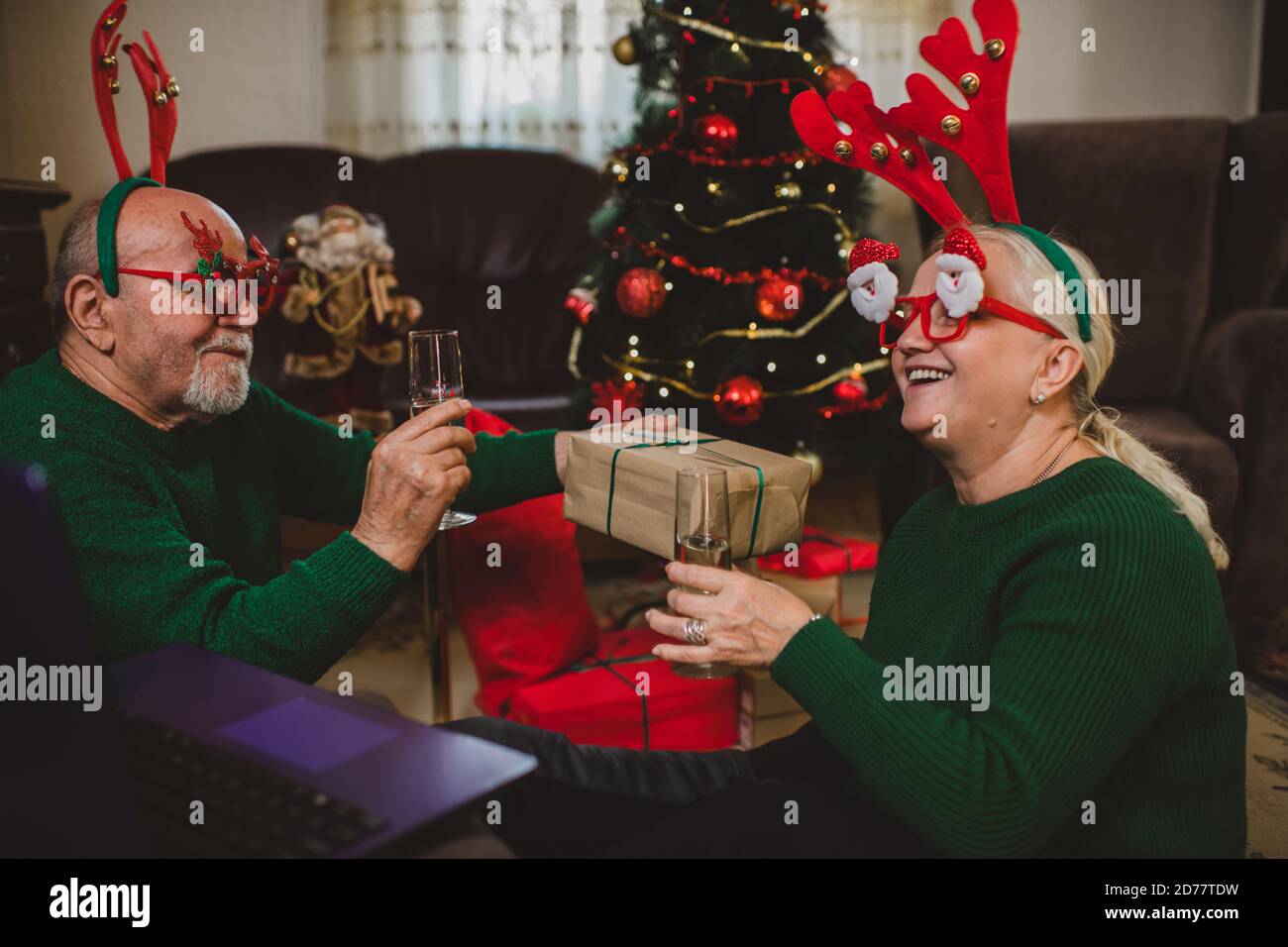 Coppia anziana a casa che ha una celebrazione di Natale su un videochiamata Foto Stock