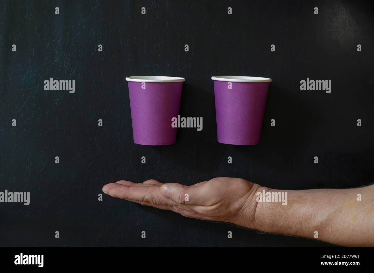 Sfondo creativo con tazze di carta per bevande calde e una mano dell'uomo. Bicchieri a mano e lilla per il caffè su sfondo nero. Vista dall'alto ad angolo. Foto Stock Sfondo creativo con tazze di carta per bevande calde e una mano dell'uomo. Bicchieri a mano e lilla per il caffè su sfondo nero. Vista dall'alto ad angolo. Foto Stock
