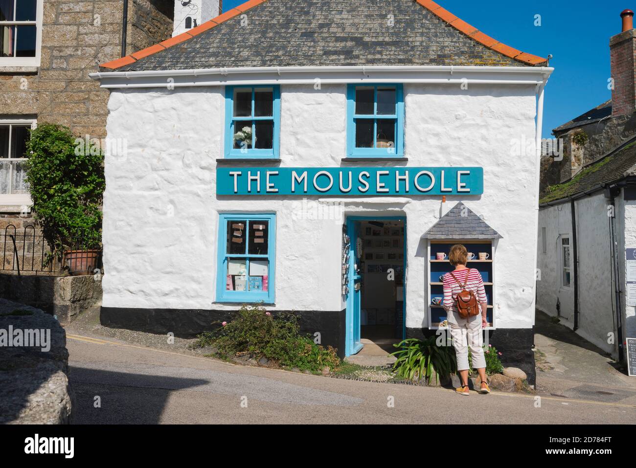 Summer Holiday UK, vista posteriore di una donna sola di mezza età che indossa uno zaino guardando un negozio di articoli da regalo in Cornovaglia, Inghilterra, Regno Unito Foto Stock