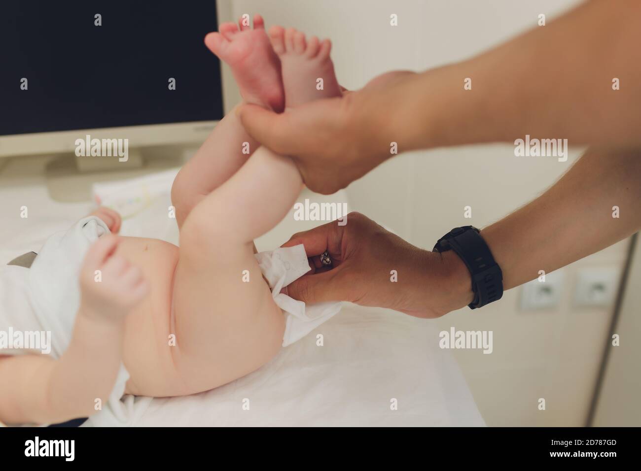 Madre che cambia il pannolino di un bambino piccolo appena si trova sulla sua parte posteriore su un tavolo cambiante nella stanza dei bambini. Igiene del bambino un tovagliolo umido. Foto Stock