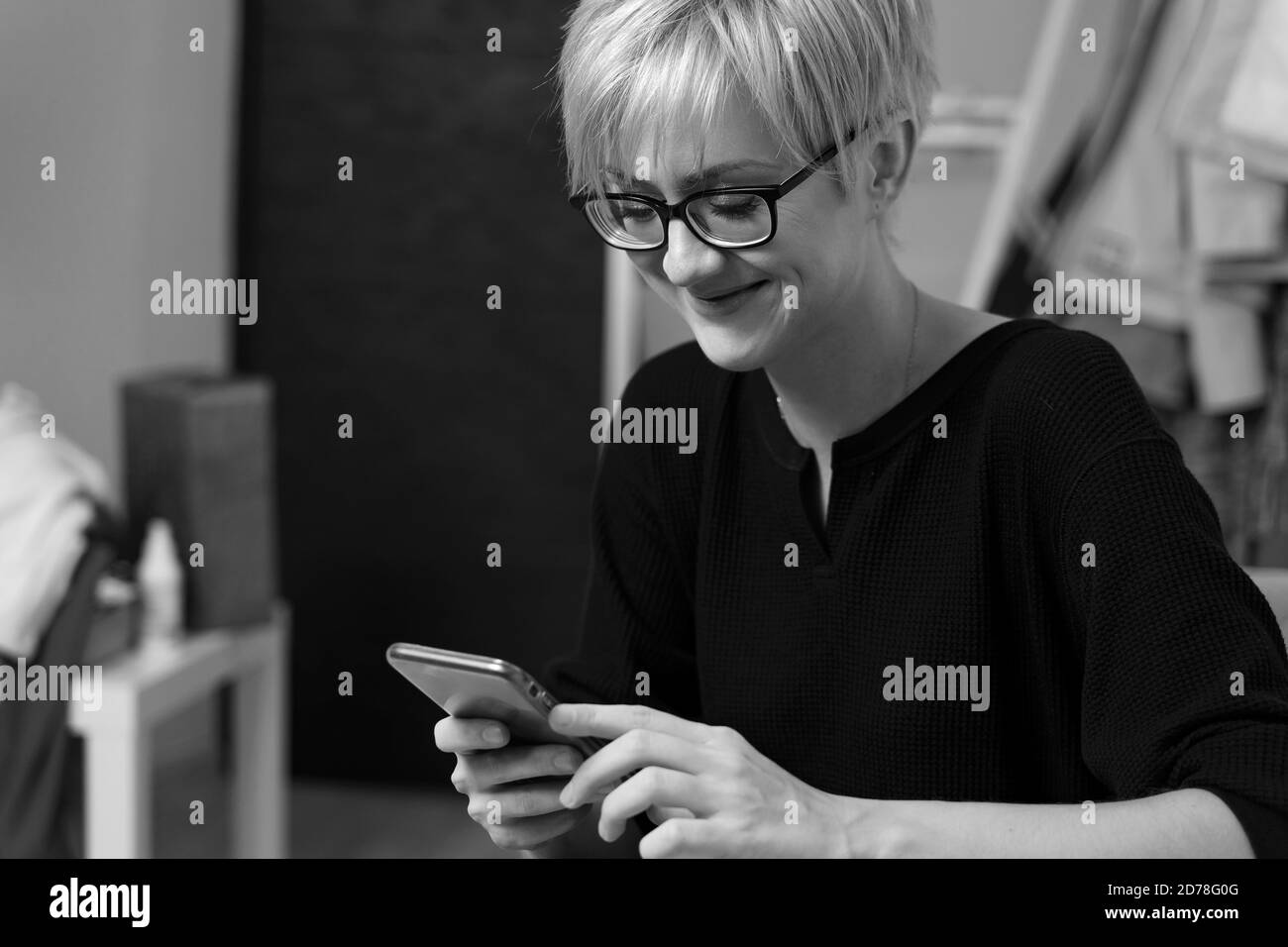 felice giovane donna sul divano tenere smartphone negozio on-line o controllare applicazioni mobili o social media. fotografia in bianco e nero Foto Stock